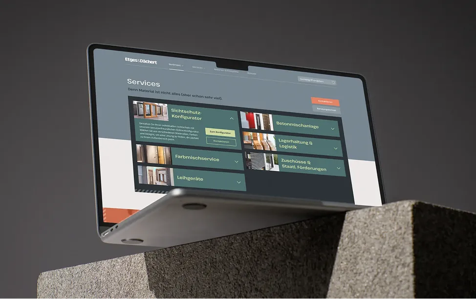 Laptop auf einem Steinblock zeigt die Services-Seite der Etges-&-Dächert-Website.